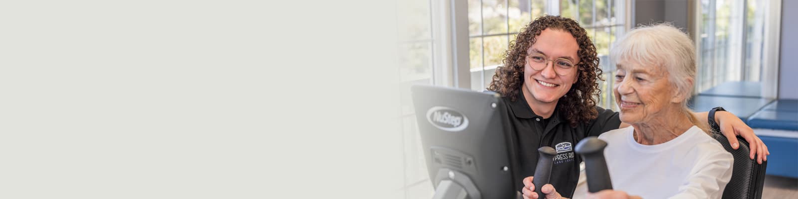 A nurse helping an elderly woman on a rehab machine