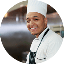 Young man wearing a chef's hat with a short beard and an apron  